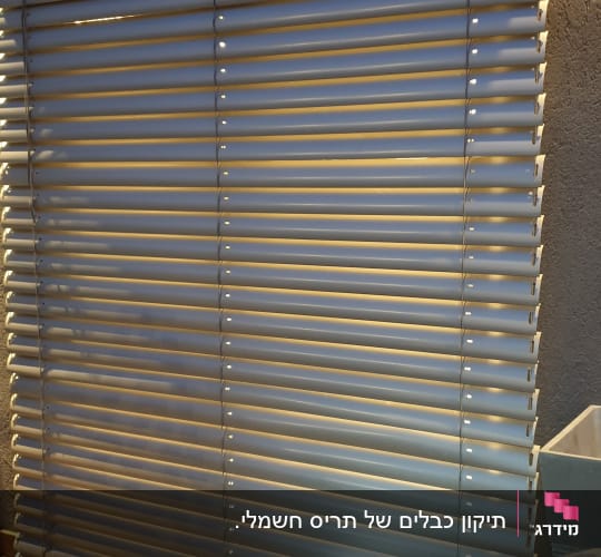 תריסים אופקיים לבנים עם אור מאחוריהם